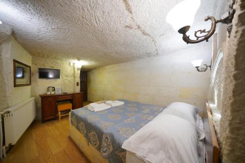 a small bedroom with a bed and a desk at Asteria Cave Hotel in Goreme
