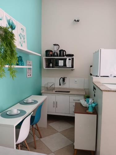 a kitchen with white cabinets and a blue wall at Hospedagem Quarto Chic centro Cunha in Cunha