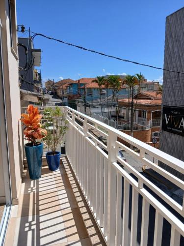 a balcony with a white railing and potted plants at Hospedagem Quarto Chic centro Cunha in Cunha