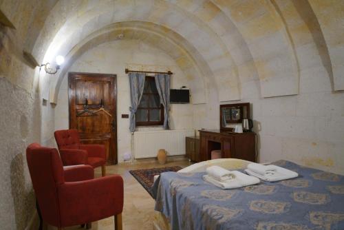 a bedroom with a bed and two chairs in a room at Asteria Cave Hotel in Goreme