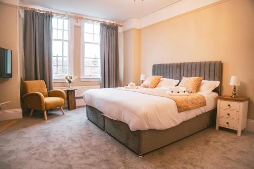 a bedroom with a large bed and a chair at St Michaels Town House - Elegant and Large Holiday Home in the Heart of Gloucester in Gloucester