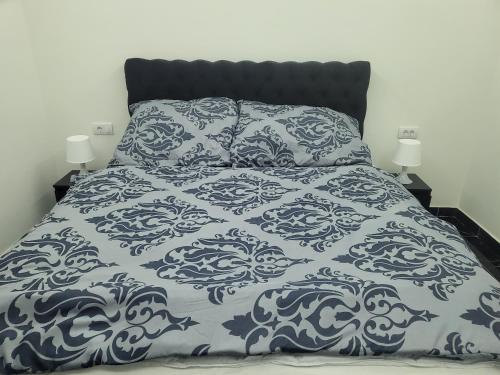 a bed with a blue and white comforter and two lamps at Jovanovic Residence Belgrad in Belgrade