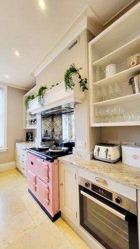 a kitchen with a pink stove and shelves at St Michaels Town House - Elegant and Large Holiday Home in the Heart of Gloucester in Gloucester