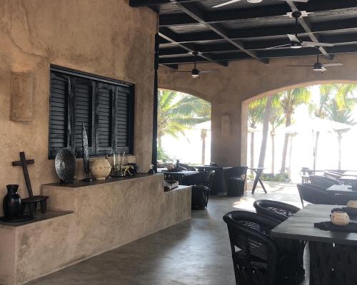 a restaurant with tables and chairs and a window at The Casa Saint George Hotel in Troncones