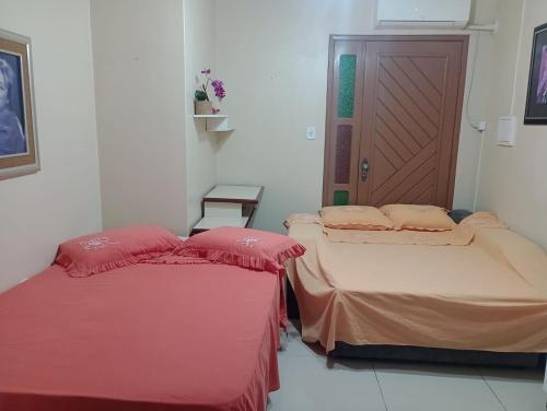 two twin beds in a room with a door at Host Family S in São Gabriel