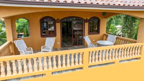 a house with a balcony with chairs and a table at Cabarete Oceanview Villa Pool Oasis Beach Access in Cafemba