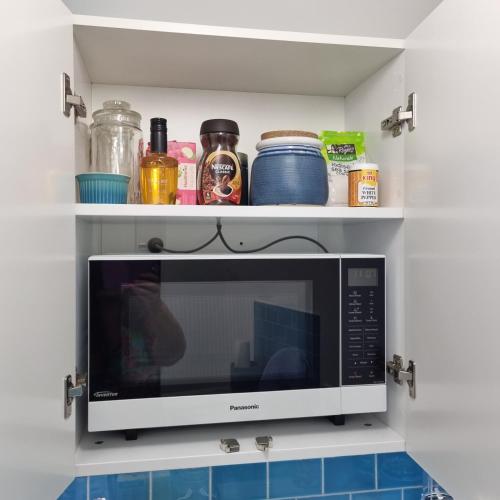 a microwave oven in a kitchen with shelves at Riverstone Retreat Upper Hutt in Upper Hutt
