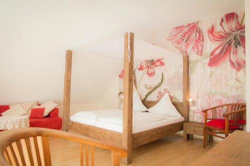 a bedroom with a canopy bed with a red chair at Weingut Weinstube Weinhotel Wolf in Harxheim