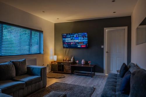 a living room with a couch and a tv on the wall at 4br-sleeps8-privategarden-freeparking in Nottingham