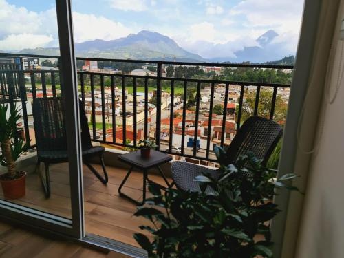 a balcony with two chairs and a view of a city at Torre La Floresta Quetzaltenango in Quetzaltenango