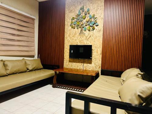 a living room with two beds and a flat screen tv at The Alusiman Home - 4 bedroom home in Iloilo City