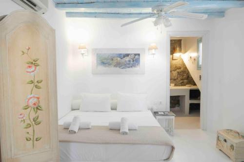 a white bedroom with a bed and a ceiling fan at Villa Schatz 2 in Mýkonos City
