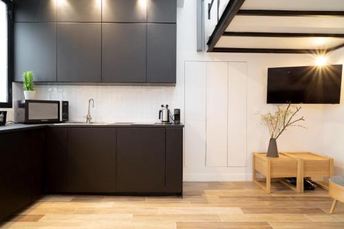 a kitchen with black cabinets and a sink and a table at Studio 5 mn from Arc de triomphe - Champs-Élysées in Paris