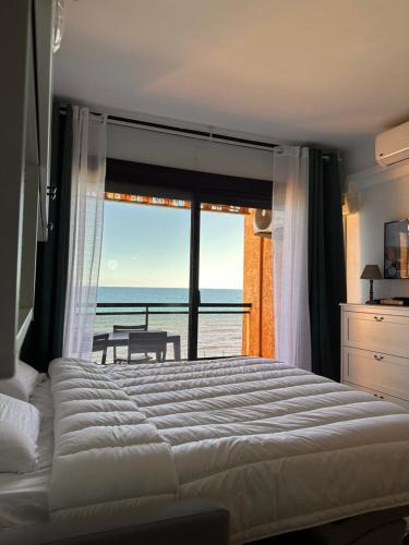 une chambre avec un lit et une vue sur l'océan dans l'établissement Studio les pieds dans l'eau, à Santa-Lucia-di-Moriani