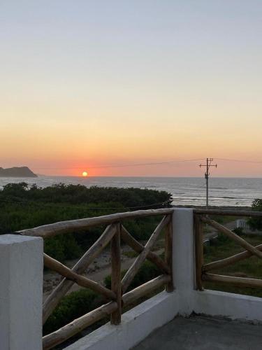 a sunset over the ocean with a wooden fence at Adonai El Roi in Juan de Acosta