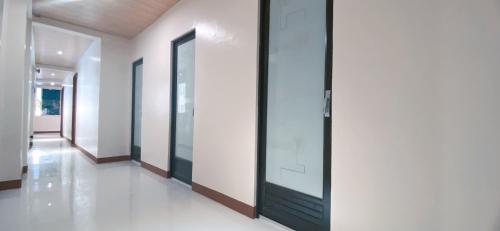 a hallway with white walls and glass doors at Pacific Guesthouse in Ubay