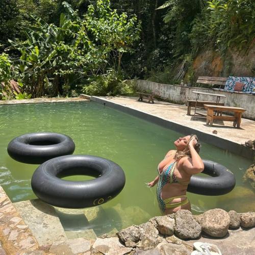 a woman in a pool of water with two inflatable tires at Refúgio Boa Sorte , Sana -Macaé RJ in Sana