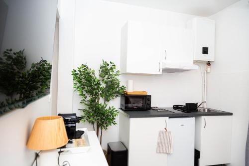 une cuisine avec des placards blancs et une table avec une lampe dans l'établissement Studio Stade de France 2 pour 2 personnes, à Saint-Denis