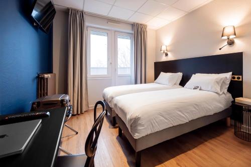 a hotel room with two beds and a desk at Hôtel du Parc Thionville Centre in Thionville