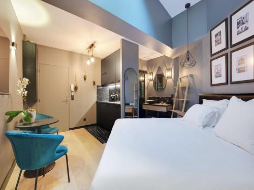 - une chambre avec un grand lit blanc et une chaise bleue dans l'établissement Charming studio -2P- Auteuil, à Paris