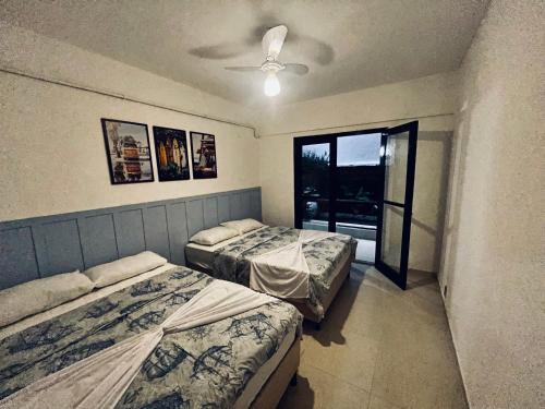 two beds in a room with a window at Meu Loft Itauna 1 - Localização Privilegiada in Saquarema