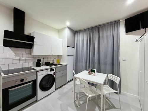a kitchen with a washing machine and a table and chairs at SÉ - BRAGA Lounge Suites COLLECTION BY PERPETUAL RELAX in Braga
