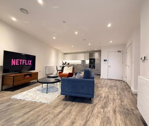 a living room with a blue couch and a tv at Skyline View Apartments - City Lights & Skyline Heights in Barking