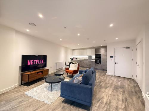 a living room with a blue couch and a tv at Skyline View Apartments - City Lights & Skyline Heights in Barking