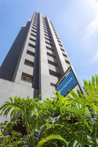 a tall building with a sign in front of it at Flat in Wyndham Paulista com estacionamento in Sao Paulo