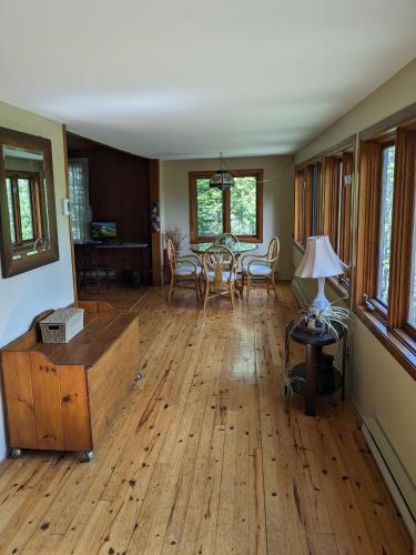 a living room with wooden floors and a table and chairs at Snowflake Escape in Val-Morin