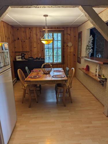 a kitchen and dining room with a table and a refrigerator at Snowflake Escape in Val-Morin