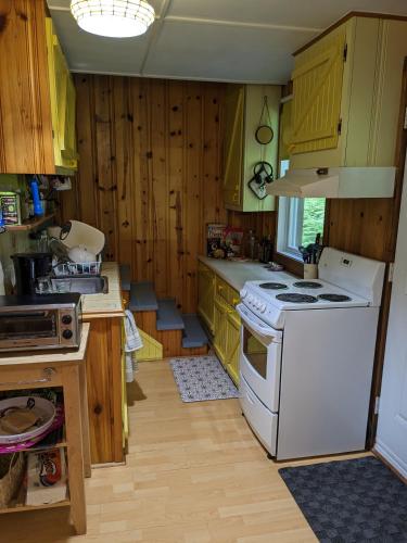 a kitchen with wooden cabinets and a white stove top oven at Snowflake Escape in Val-Morin