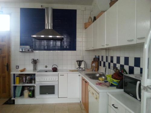 a white kitchen with a sink and a stove at El Refugio del Dragón in Arcones