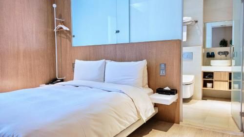 a bedroom with a large white bed and a bathroom at Hotel Mapp in Taichung