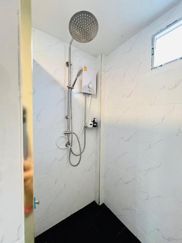 a shower in a bathroom with white tiles at อาวารินวิลล่า Awarin villa in Ban Tanjong In