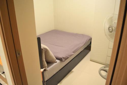 a small bed in a small room with a fan at Callie's Cozy Home at Shore 3 Mall of Asia in Manila
