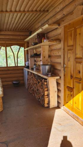 a kitchen in a wooden cabin with a stack of logs at Таежный домик Васильево in Poperechnoye