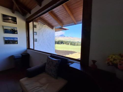 a living room with a couch and a large window at Cotopaxi Lodge in Hacienda Porvenir