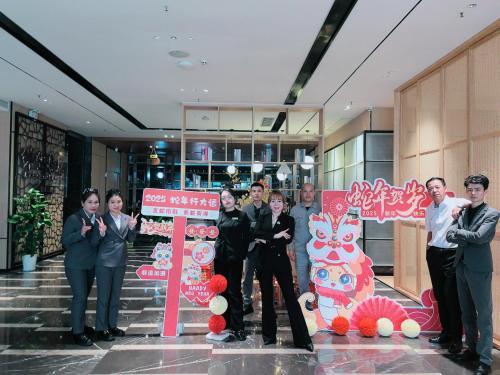 a group of people standing next to a sign at 宜尚酒店 日月广场骑楼老街店 in Haikou