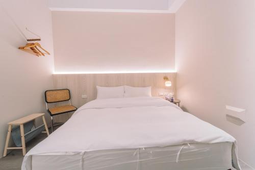 a bedroom with a large white bed and a chair at 玉井拱月民宿 in Yujing