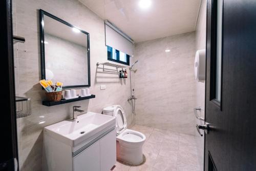 a bathroom with a toilet and a sink and a mirror at 玉井拱月民宿 in Yujing