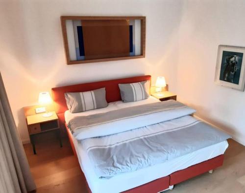 une chambre avec un lit avec une tête de lit rouge et un miroir dans l'établissement Residenz-Am-Wald-Nr-2-0, à Sankt Peter-Ording