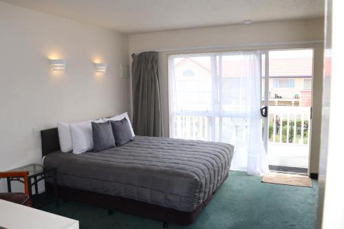 a bedroom with a bed and a large window at BK's Fountain Court Motel in Napier
