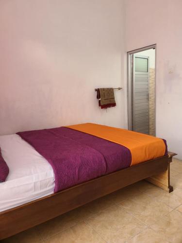 a bedroom with a large bed with colorful sheets at Rumah Mawar Syariah in Bukittinggi