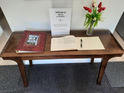 a wooden table with a book and a vase of flowers at Villa One on Fitzherbert in Palmerston North
