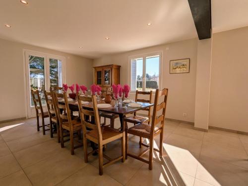 une salle à manger avec une table ornée de fleurs roses dans l'établissement Gîte spacieux pour 10 pers. avec grand jardin à Tence - FR-1-582-528, à Tence