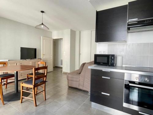 Il comprend une cuisine et un salon avec une table et un four micro-ondes. dans l'établissement Moderne T2 avec Balcon & Garage à Aix-les-Bains - FR-1-555-110, à Aix-les-Bains