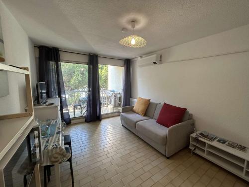 un salon avec un canapé et une grande fenêtre dans l'établissement Studio Cabine Proche Plage avec Terrasse - Le Grau-du-Roi - FR-1-250-297, au Grau-du-Roi