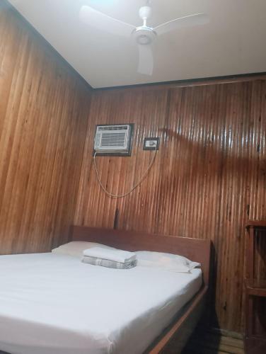 a bedroom with a bed with a wooden wall at Naramalan Inn in San Vicente