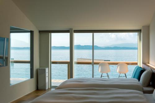a bedroom with a large bed and two chairs at Umikara , Obama Ocean Suite in Unzen